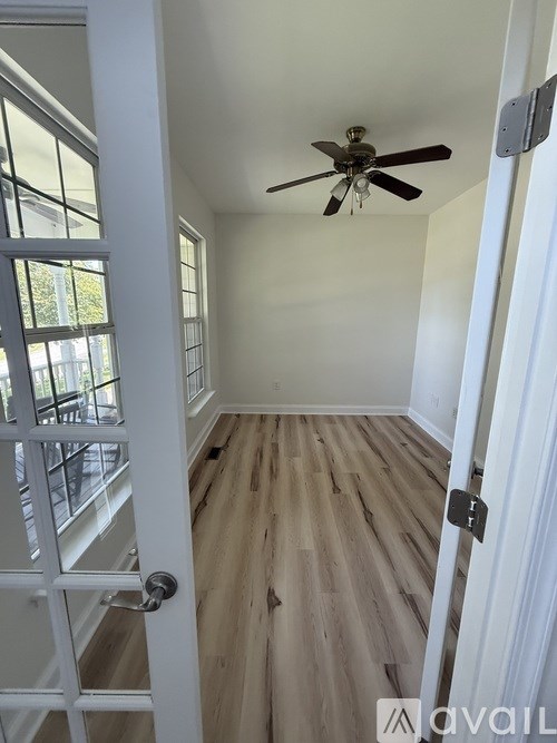 A room with a ceiling fan and wooden flooring.
