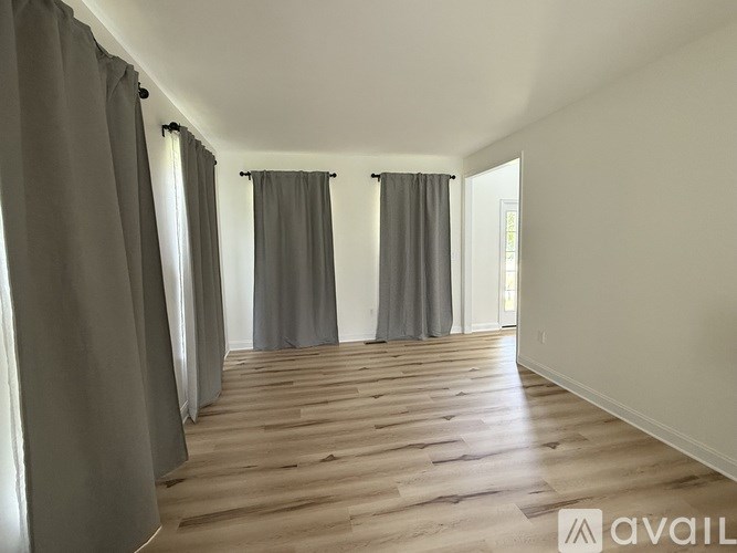 A room with wooden flooring and grey curtains.