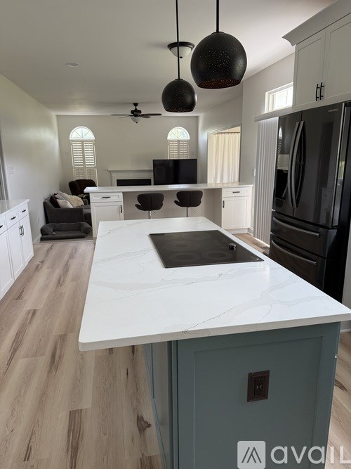 A kitchen with a white countertop and a black refrigerator.