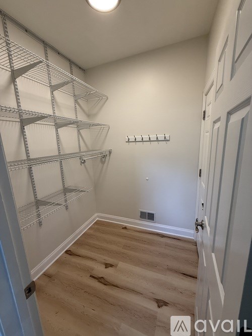 A white wall with a door and a shelf.
