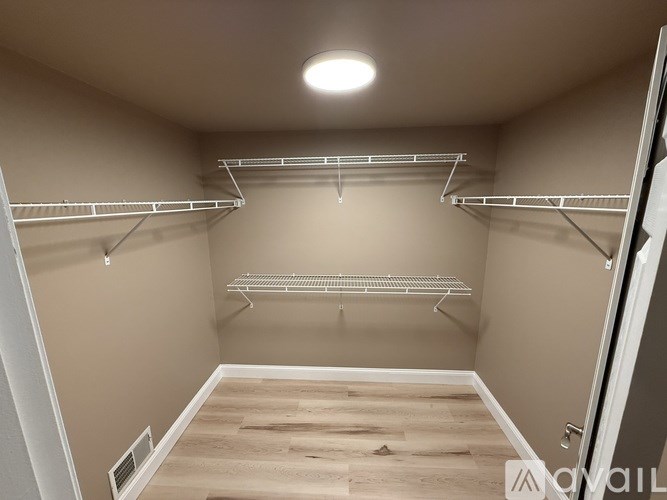 A spacious walk-in closet with wooden floors and metal racks.