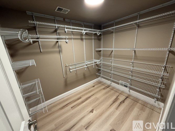 A large, empty room with a lot of shelving and a door on the left.