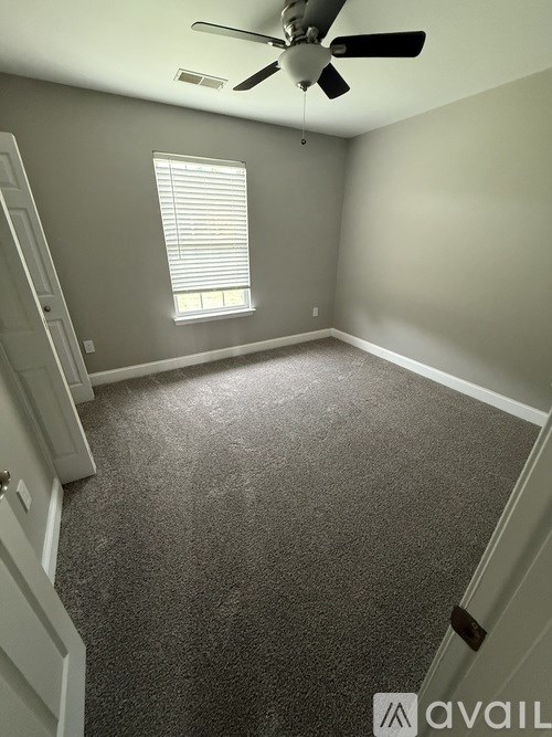 A room with a ceiling fan and a window with blinds.