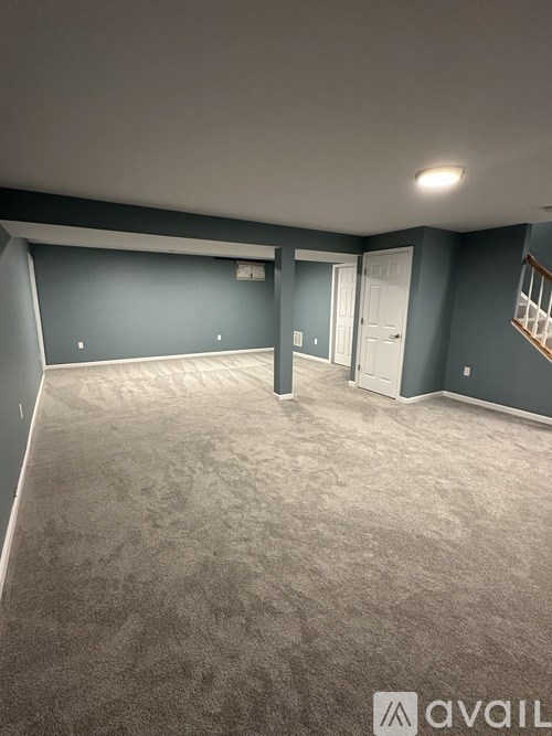 A room with grey carpet and blue walls is available for rent.