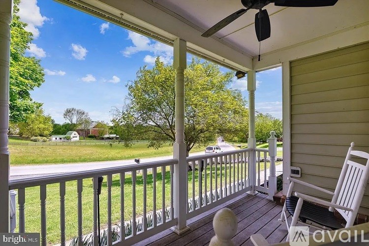 A porch with a white chair and a fan.