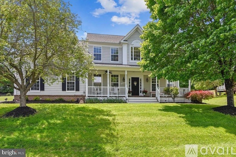 A large house with a front porch and a tree in front.