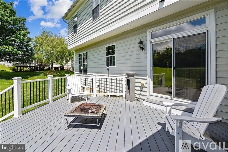 A wooden deck with a table and chairs is in front of a house.
