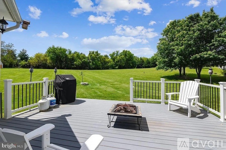 A wooden deck with a white railing and two chairs.