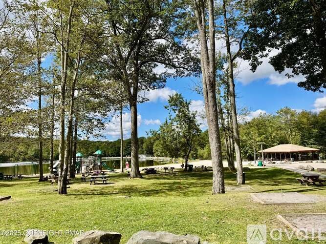 A park with a gazebo, picnic tables, and tall trees.