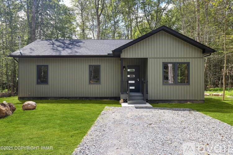 A small house with a grey roof and a gravel pathway leading to the front door.
