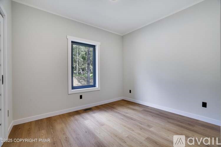 A room with a window and wooden flooring.