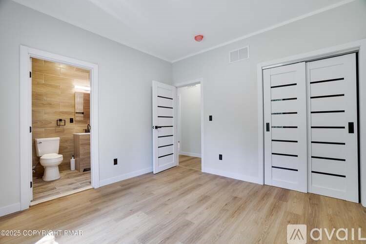 A bathroom with a toilet, sink, and a wooden accent wall.