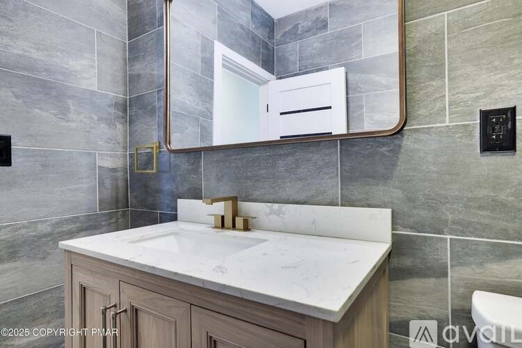 A bathroom with a marble countertop and a large mirror above it.