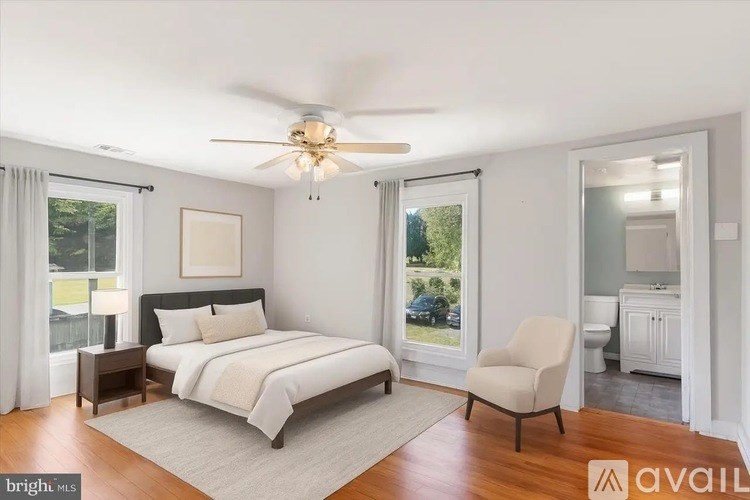 A bedroom with a bed, chair, and a ceiling fan.