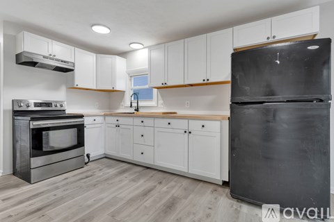 A kitchen with white cabinets and a black fridge.