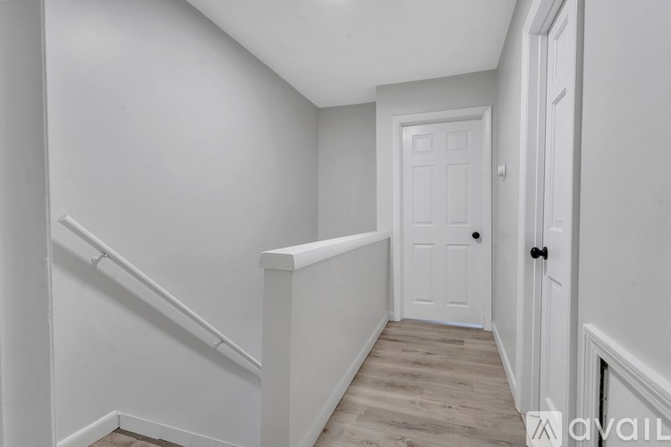 A white door is in a hallway with wood flooring.