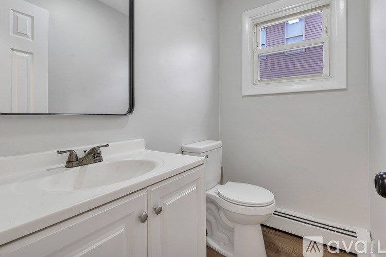 A white bathroom with a toilet, sink, and mirror.