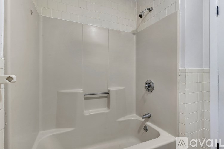 A white bathtub with a shower head and faucet.