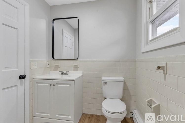 A white bathroom with a toilet, sink, and mirror.