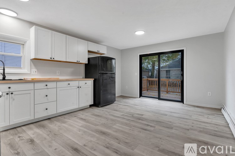 A kitchen with white cabinets and a black refrigerator.