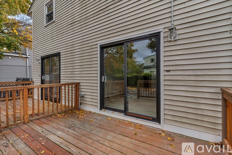 A wooden deck with a glass door and windows on a house.