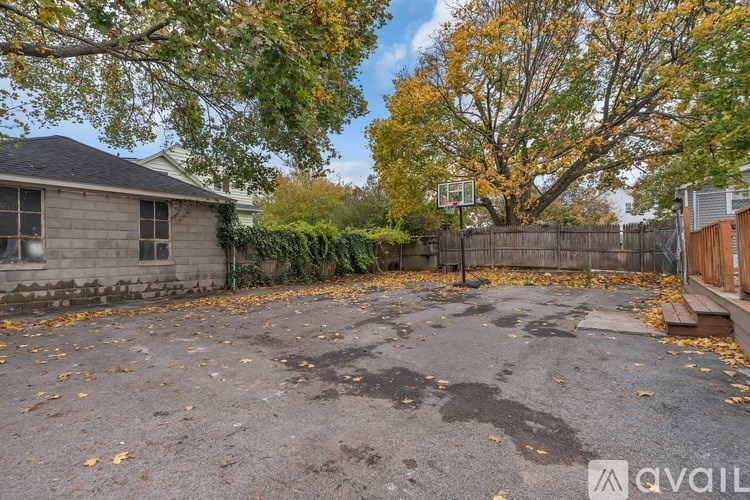 A basketball court surrounded by a fence and trees with fallen leaves.