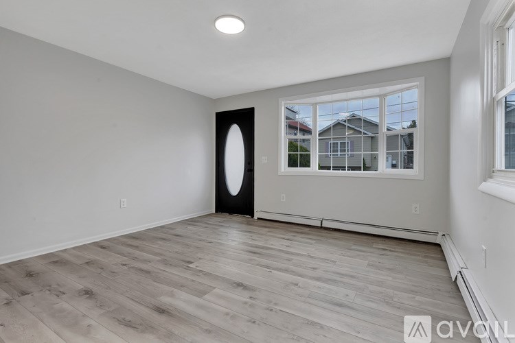 A spacious room with wooden flooring and a large window.