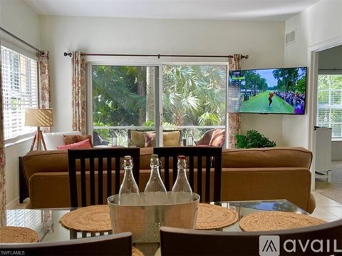 A living room with a couch, chairs, and a television displaying a golf game.