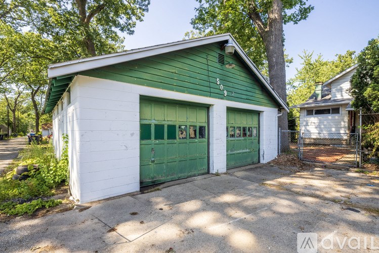 A green and white garage with a white fence in front.
