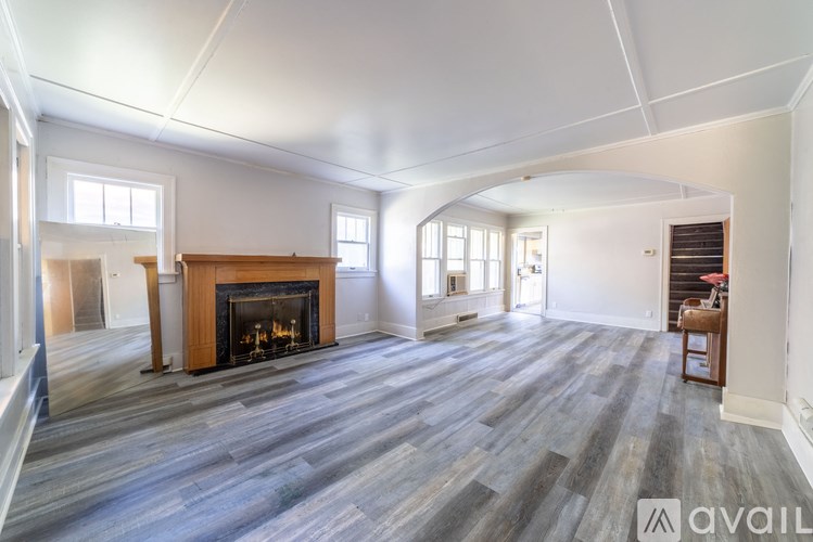 A spacious living room with a fireplace and wood flooring.