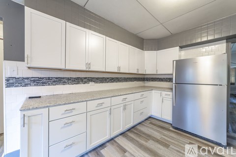 A kitchen with white cabinets and a stainless steel refrigerator.