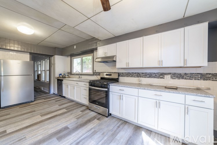 A kitchen with white cabinets and a stainless steel refrigerator.