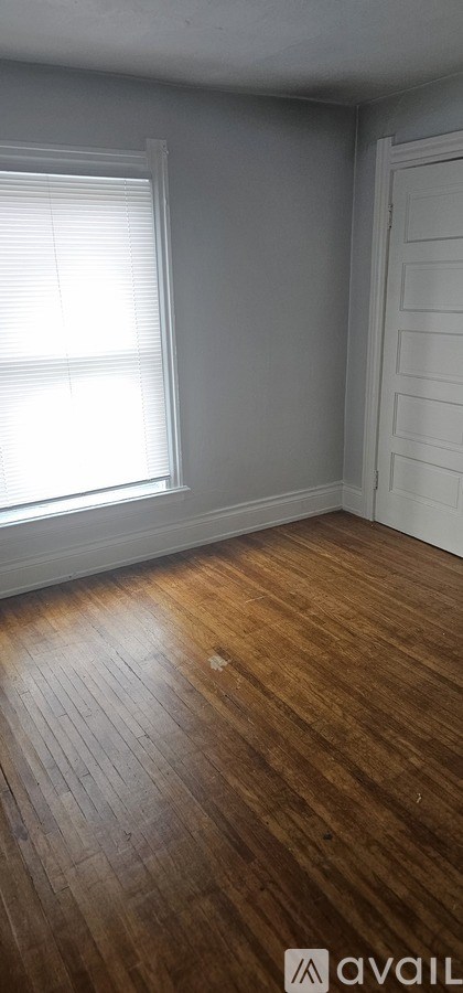A room with wooden flooring and a window with blinds.