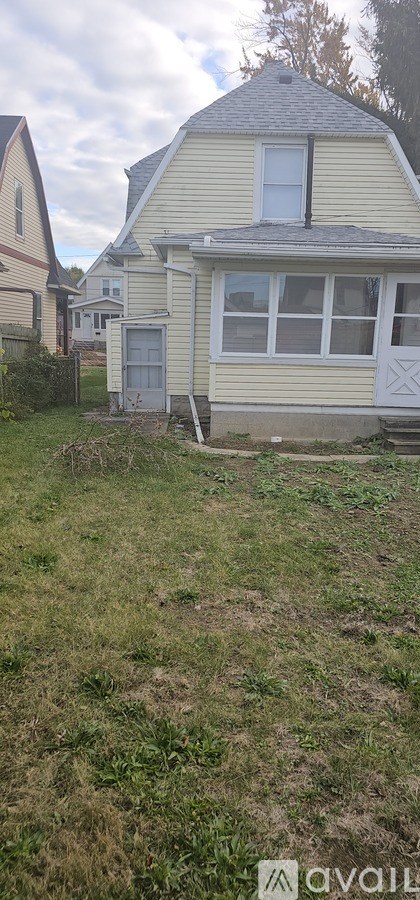 A house with a white door and a window is surrounded by grass.