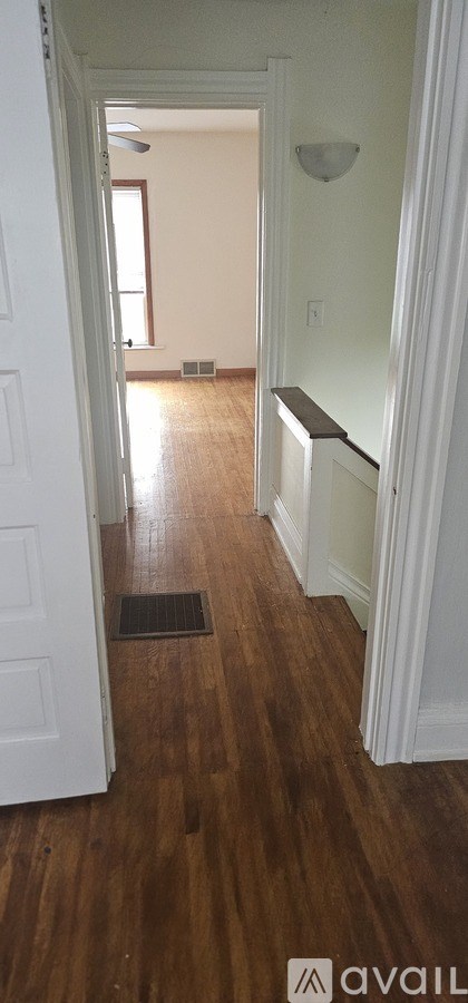 A hallway with a white door and wooden floors.