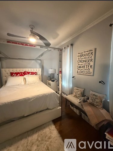 A bedroom with a bed, a bench, and a fan.