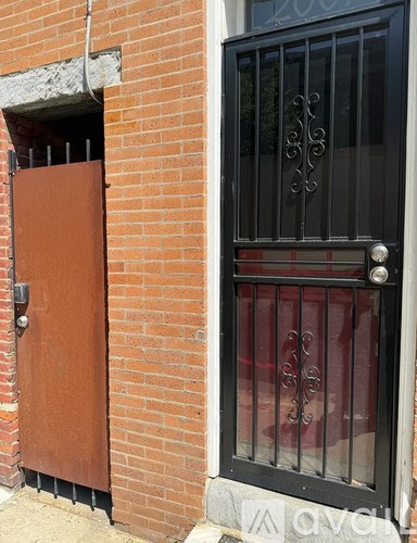 A brown door is open to a brick wall.