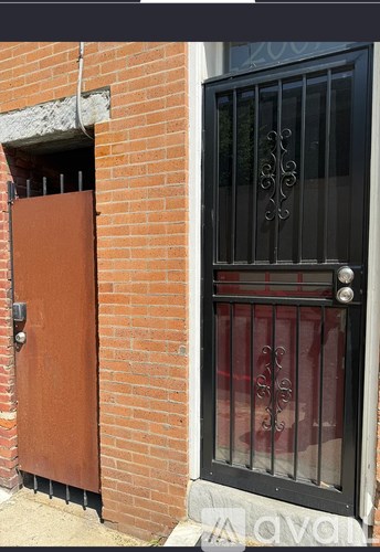 A black gate with a metal handle is on a brick wall.
