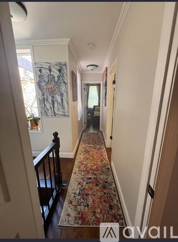 A hallway with a floral carpet and a painting on the wall.