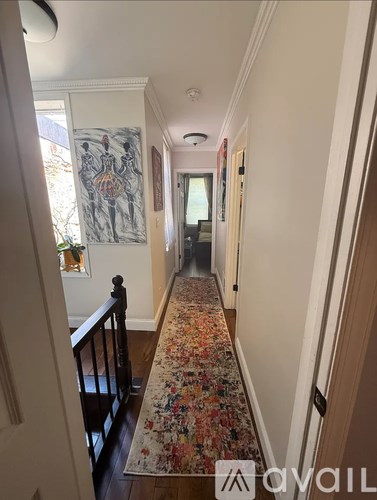 A hallway with a floral carpet and a painting on the wall.