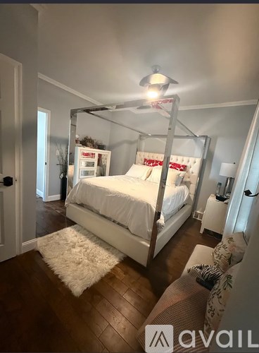 A bedroom with a four poster bed and a white rug on the floor.