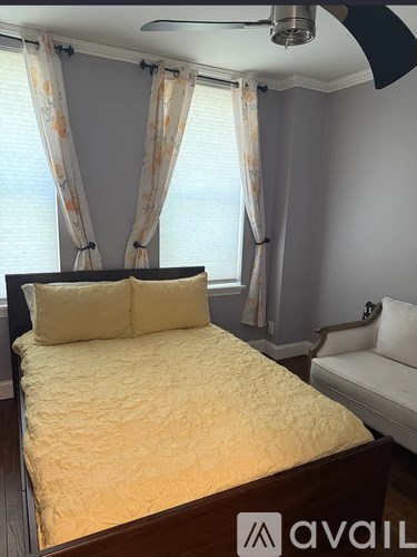 A bedroom with a bed, a chair, and a window with curtains.