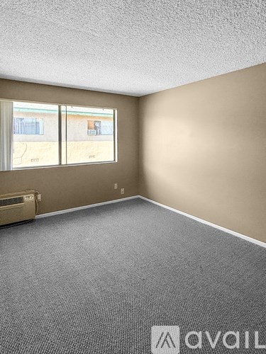 A room with a carpeted floor and a window overlooking a parking lot.