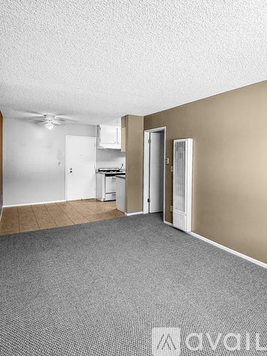 A room with a carpeted floor and a white ceiling fan.