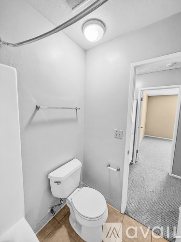 A white toilet in a small bathroom with a white wall and a white door.