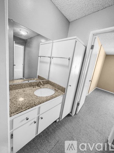 A bathroom with a sink, mirror, and cabinets.