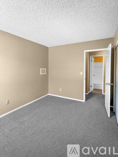 A room with a carpeted floor and a doorway leading to another room.