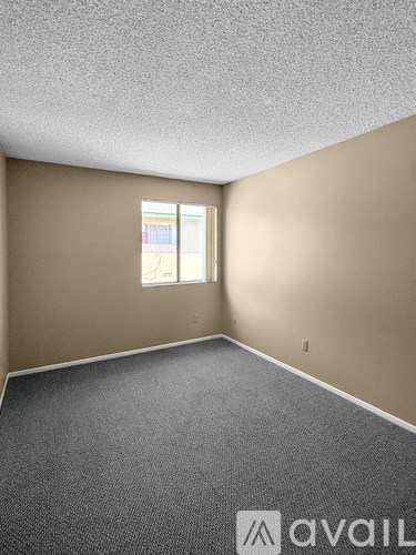 A room with a carpeted floor and a window with blinds.