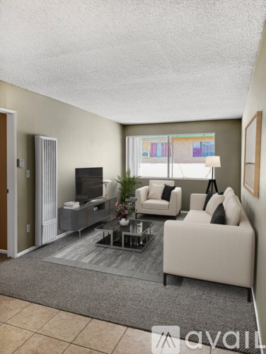 A living room with a white couch, a coffee table, and a television.