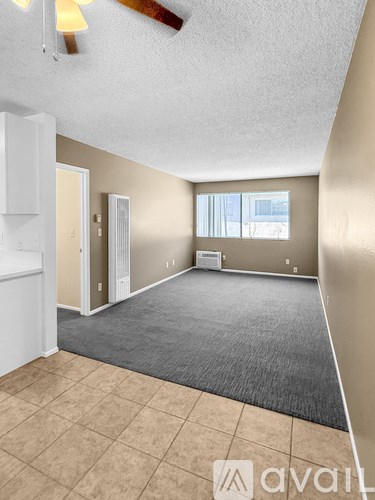 A room with a carpeted floor and a window with blinds.